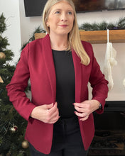 Load image into Gallery viewer, Woman wearing a red blazer over a black top in a festive indoor setting with Christmas decorations.