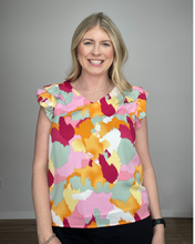 Load image into Gallery viewer, Woman wearing a v-neck sleeveless tank with shoulder ruffles and a watercolor print with dark pink, light pink, seafoam green, white, yellow, and orange colors.