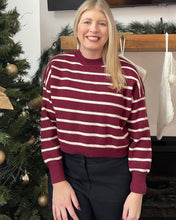 Load image into Gallery viewer, Woman in a burgundy and ivory cropped long sleeved sweater by a Christmas tree