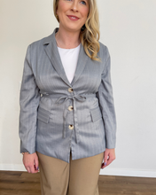 Load image into Gallery viewer, Woman wearing a light blue pinstripe blazer with a belt, white shirt, and beige pants against a plain background.