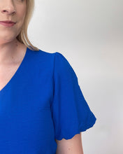 Load image into Gallery viewer, Close up of a short sleeve royal blue shirt with a v neck and puff sleeves.
