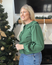 Load image into Gallery viewer, Woman in a green top standing next to a decorated Christmas tree indoors.
