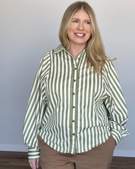 Woman in a long sleeve button up shirt with pistachio green and ivory vertical stripes. Blouse has puff sleeves.