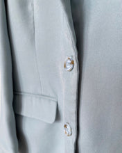 Load image into Gallery viewer, close up of a light blue, long sleeve solid woven blazer with an open front featuring functional blue and tan tortoise shell buttons and pockets
