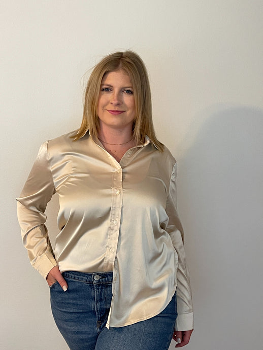 Blonde woman wearing champagne colored satin button-down collared shirt with button cuffed long sleeves