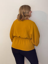 Load image into Gallery viewer, Back of woman in mustard color blouse with elastic waist
